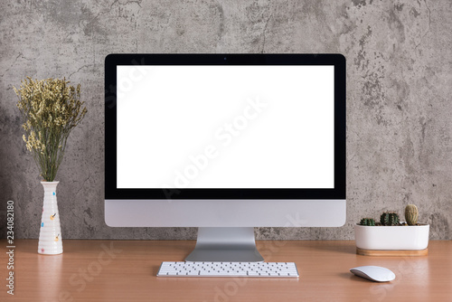 Blank screen of all in one computer with dry flowers and cactus vase on raw concrete background