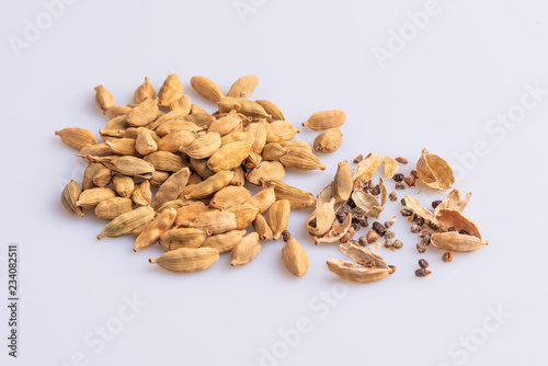 Dry Cardamom pod in a stone mortar, isolated on white background, latin term Elettaria cardamomum, with copy space, angle view, soft light. 