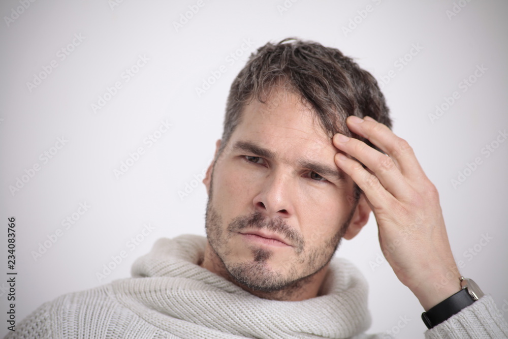 Man in white sweater touching his hair in front of a white background Man in white sweater touching his hair in front of a white background