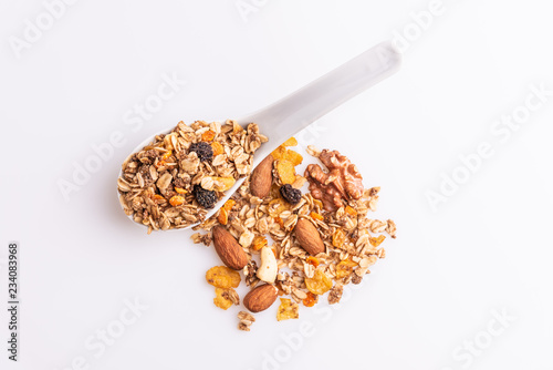 Granola or muesli with nuts and rasins in a white spoon on a white background, top view, soft light photo