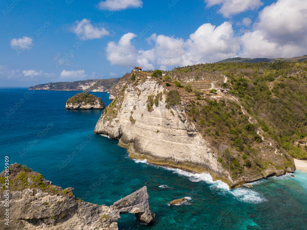 Aerial view to beautiful arched rock in ocean and Atuh cliff. Photo from drone. Nusa Penida, Bali, Indonesia