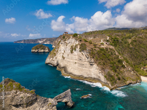 Aerial view to beautiful arched rock in ocean and Atuh cliff. Photo from drone. Nusa Penida, Bali, Indonesia