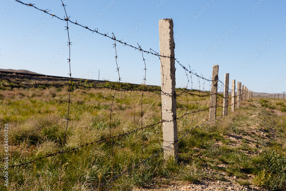 fence of barbed wire that separates the railway from the steppe, Mongolia