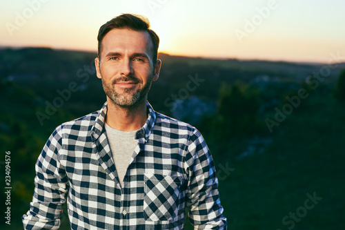 Portrait of handsome man standing on meadow surrounded by nature #234094576