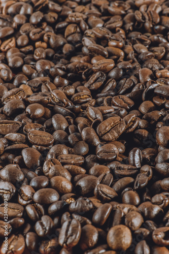 Background a lot of coffee whole grains lies. Vertical toned photography