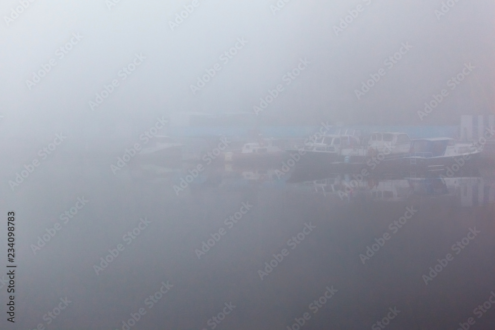 boats at the pier on the river in heavy dense fog