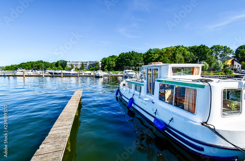 Houseboats and yachts are moored in Goehren-Lebbin (Germany) at a jetty of the lake Fleesensee