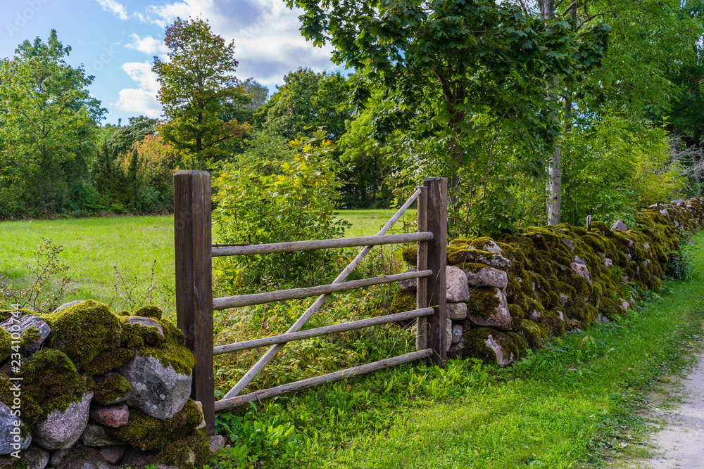 Rock fence and a wooden gate at the meadow