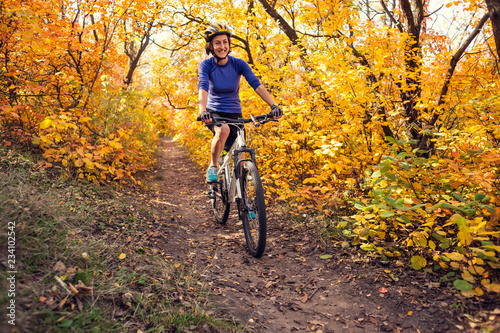The girl rides a bike in the autumn park.