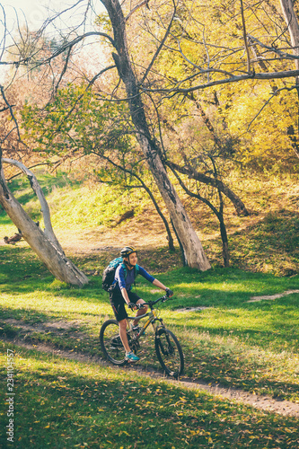 The girl rides a bike in the autumn park.