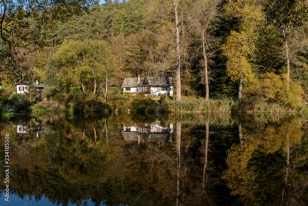 Cottages and small houses among the trees reflected on the surface of the river Sazava