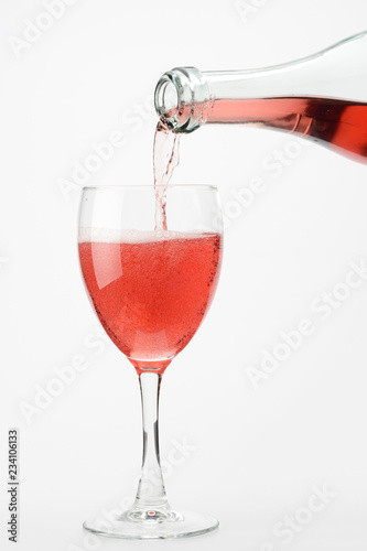 Vertiendo vino rosado lambrusco en una copa sobre fondo blanco