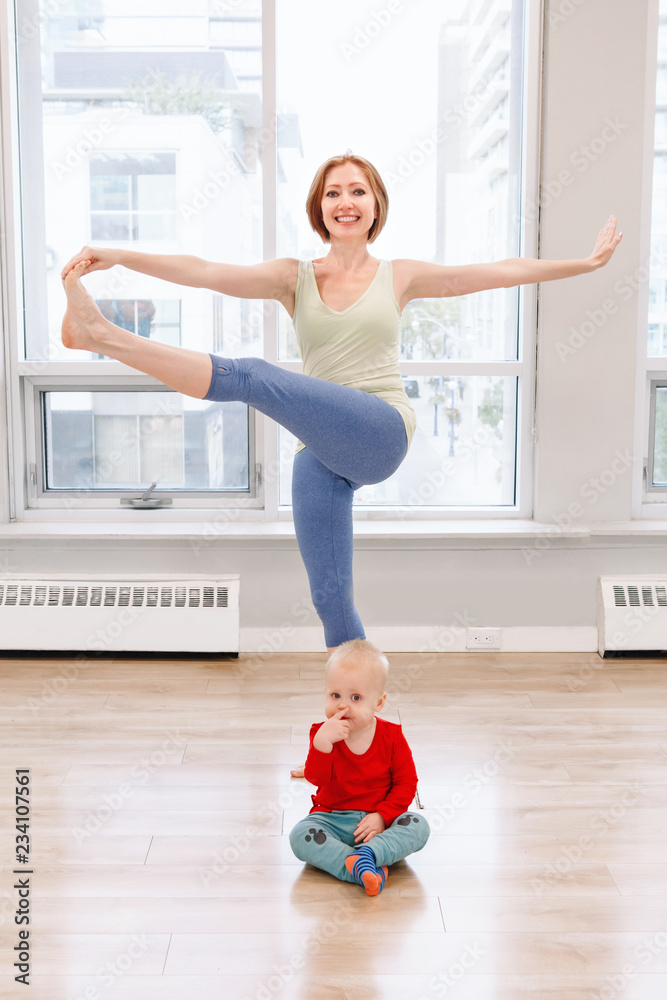 Young woman with child boy son doing workout in gym class to loose baby weight. Child-friendly fitness for mothers with kids toddlers. Lifestyle concept of family activity indoors. Young woman with child boy son doing workout in gym class to loose baby weight. Child-friendly fitness for mothers with kids toddlers. Lifestyle concept of family activity indoors.