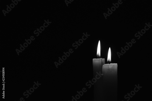 Candle burning in the black background. Black and white photo.