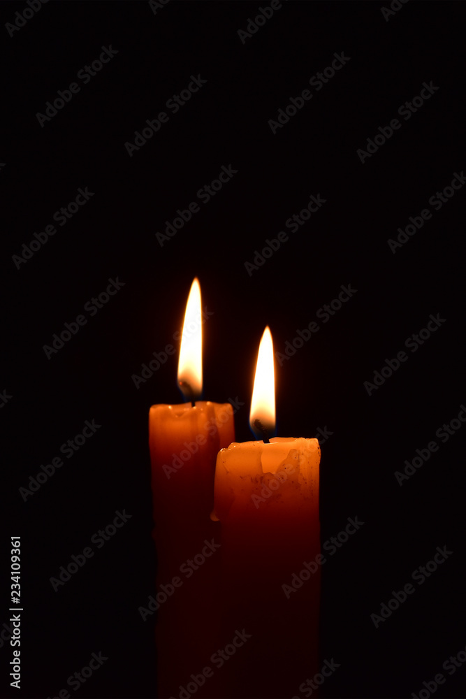 Yellow light candle burning brightly in the black background. Yellow light candle burning brightly in the black background.