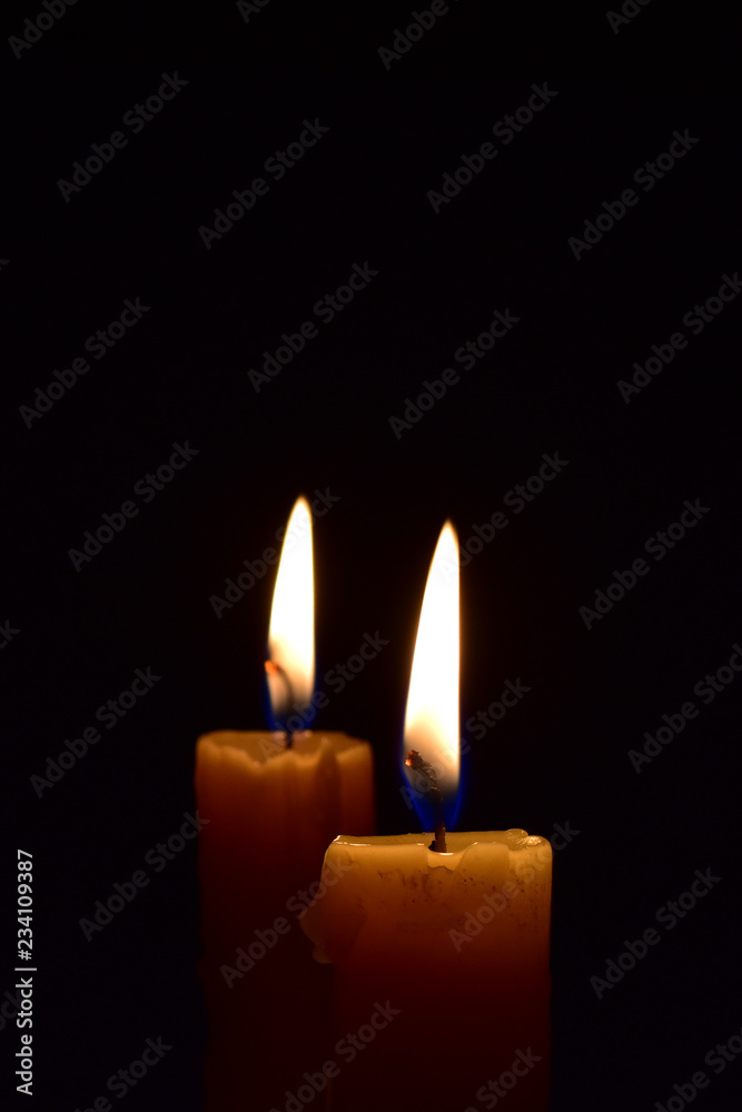 Yellow light candle burning brightly in the black background. Yellow light candle burning brightly in the black background.
