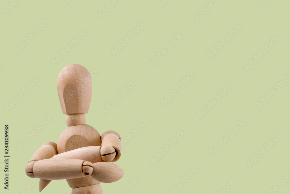 Wooden dummy holds two hands crossed in judgemental pose light green background Wooden dummy holds two hands crossed in judgemental pose light green background