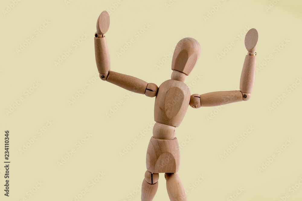 Wooden dummy holds two hands in air on light yellow background Wooden dummy holds two hands in air on light yellow background