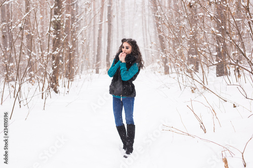 Young pretty woman walking in the winter snowy park at sunny day © satura_