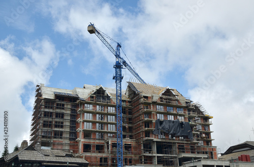 Building under construction with a crane against blue sky with clouds