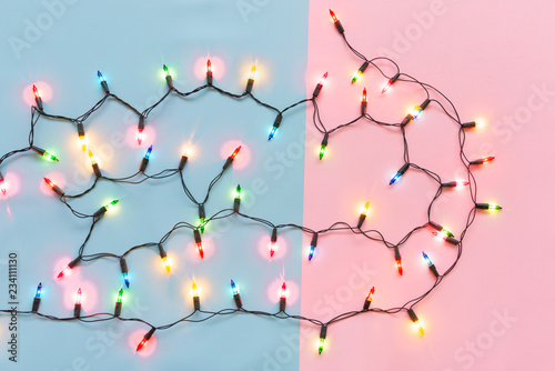 Christmas light bulbs were turned on or lid on string in colours; blue, yellow, red, pink, orange and green over pink & blue background, sweet holiday concept for Xmas or special love celebration