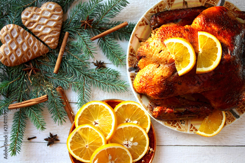 Pieczona kaczka z pomarańczami otoczona gałązkami świerku, piernikami i gwiazdkami anyżu, świąteczny obiad w Boże Narodzenie