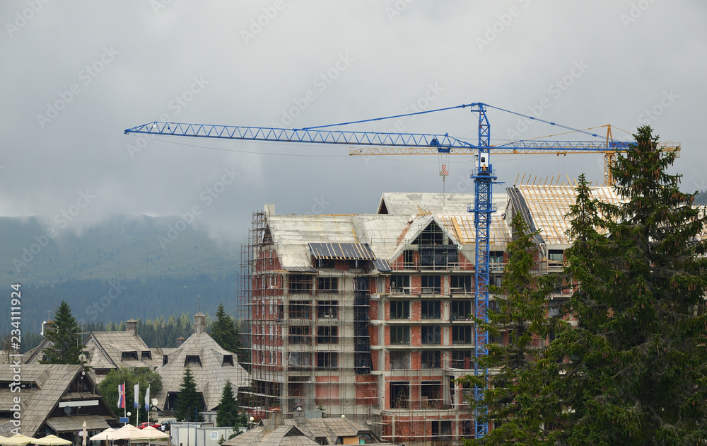 Building under construction with a crane against cloudy sky