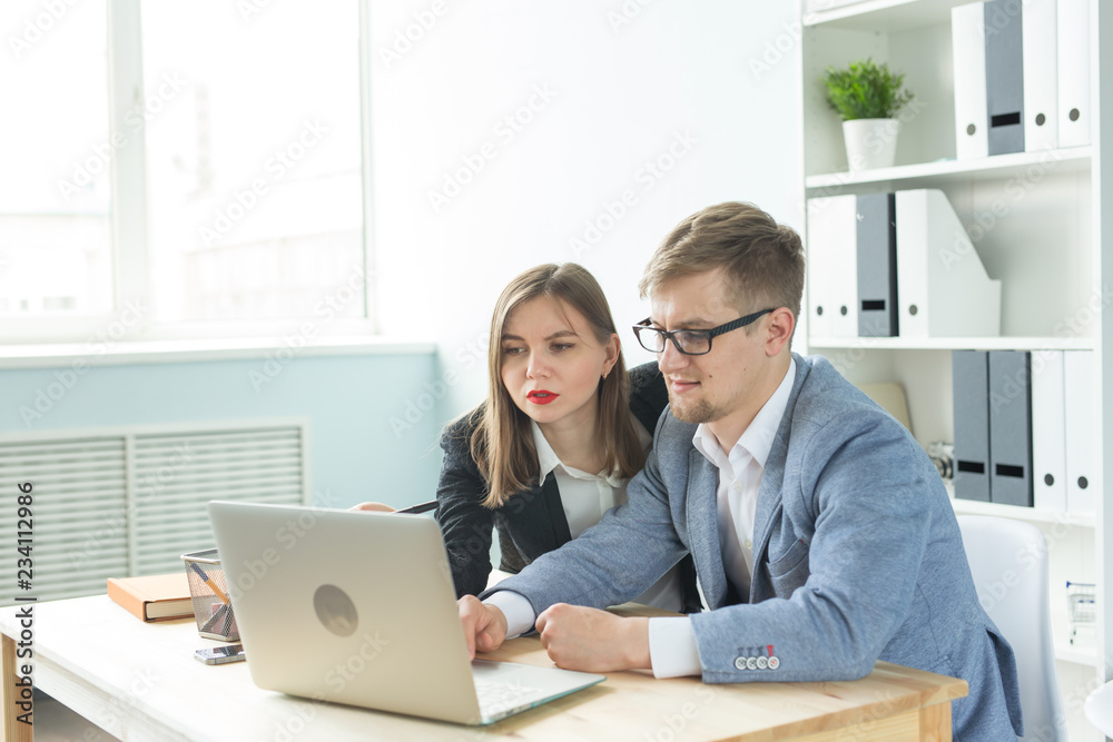 Business people, team work and office concept - woman and man are working at startup project together in office Business people, team work and office concept - woman and man are working at startup project together in office