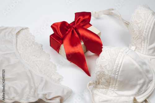 Fotografía top view silk lingerie and gift with red satin ribbon flat lay