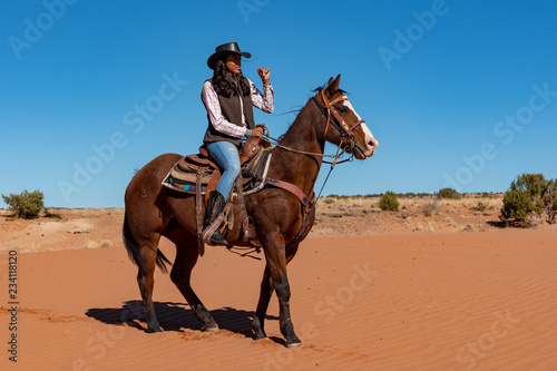 young native american woman riding horse in the desert