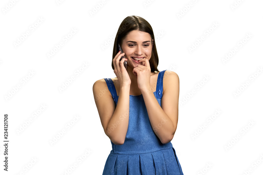 Young flirty woman talking on phone. Joyful girl talking on cell phone while touching her lips, isolated on white background. Young flirty woman talking on phone. Joyful girl talking on cell phone while touching her lips, isolated on white background.