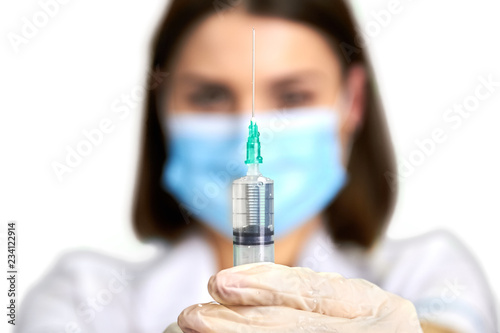 Female doctor holding syringe, selective focus. Plastic syringe with injection in nurse hand isolated on white background.