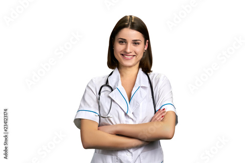 Young cheerful doctor on white background. Female medical worker standing with arms folded. Pretty female practitioner. © DenisProduction.com