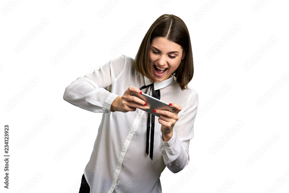 Funny business woman playing on smartphone. Happy positive caucasian girl plays online game on her cell phone, isolated on white background. Funny business woman playing on smartphone. Happy positive caucasian girl plays online game on her cell phone, isolated on white background.