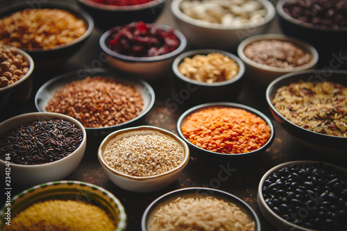 Various superfoods in smal bowls on dark rusty background. Superfood as rice, lentil, beans, peas, goji, flaxseed, buckwheat, couscous, chickpeas Above view Flat lay © Dash