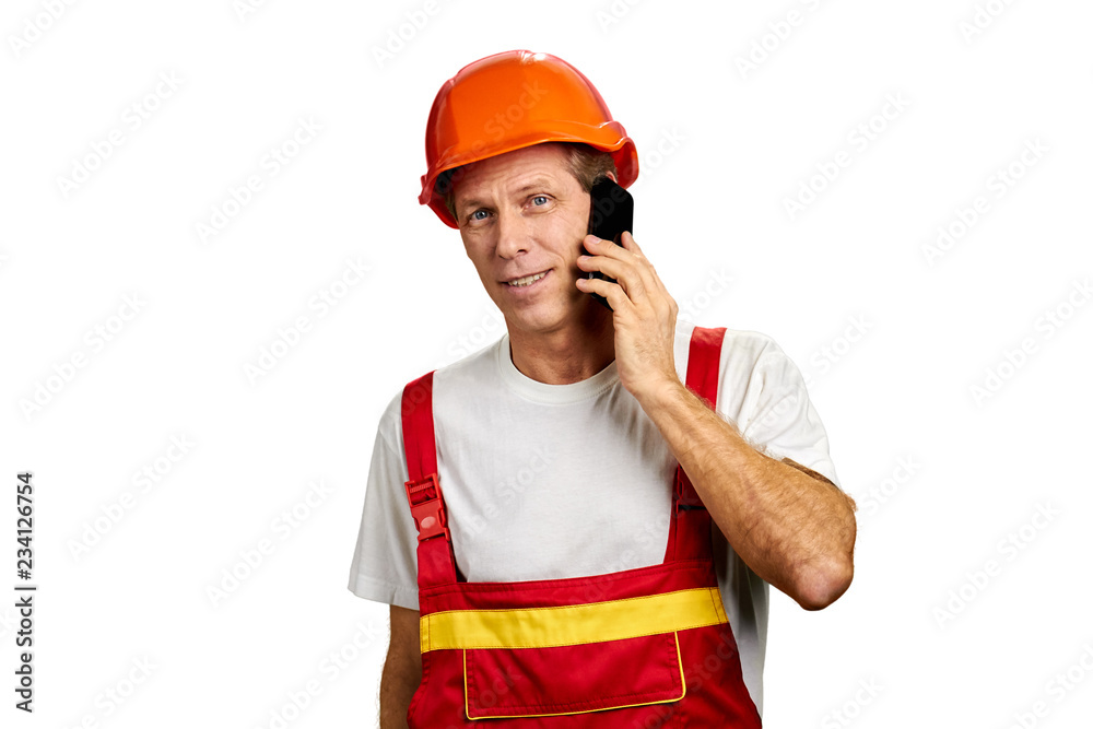 Builder talks on smartphone. Portrait of male caucasian architect in hard hat using mobile phone isolated on white background. People, construction, maintenance.