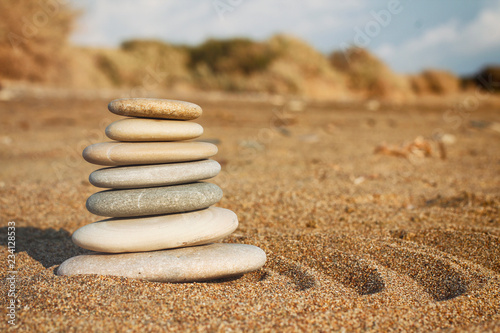 Stones pyramid balance on sand and blurred background. Spa therapy theme. Sea view. Beach. Zen garden.