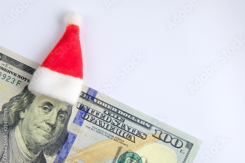 The concept of New Year's holidays and finance. US hundred dollar bill on a white background. Santa Claus hat on the head of President Franklin. Copy space.
