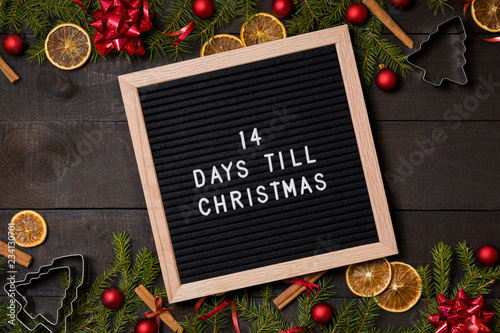 Fourteen Days till  Christmas 2 weeks  countdown letter board on dark rustic wood background with Christmas decoration and fir branch frame top view flatlay