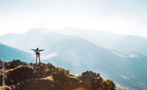 Mountain hiker with backpack tiny figurine stands on mountain peak
