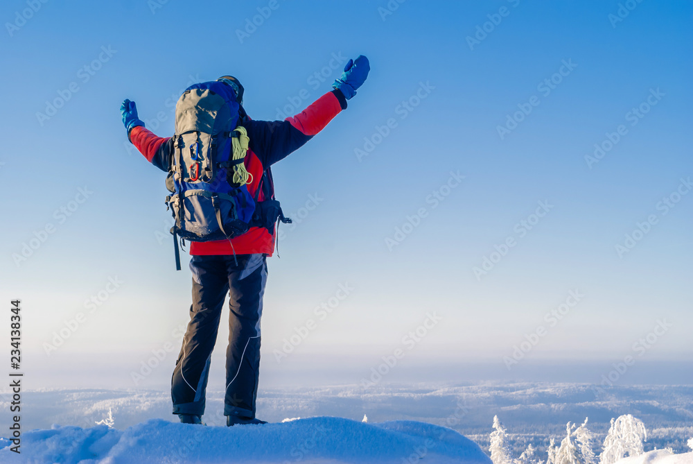traveler man with backpack standing on top of a hill enjoying a beautiful winter landscape