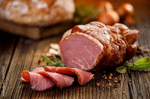 Smoked meat, Sliced smoked gammon on a wooden  table with addition of fresh  herbs and aromatic spices.   Natural product from organic farm, produced by traditional methods