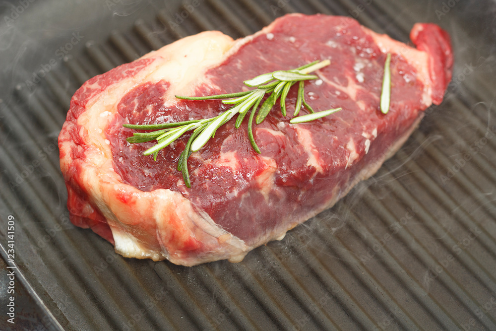 New-York Steak on frying grill panwith rosemary , top view