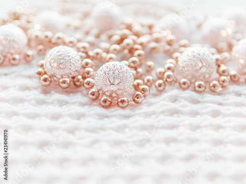 Christmas and New Year decorations on white knitted background. Metal light bulbs with delicate pattern, pale beige beads.