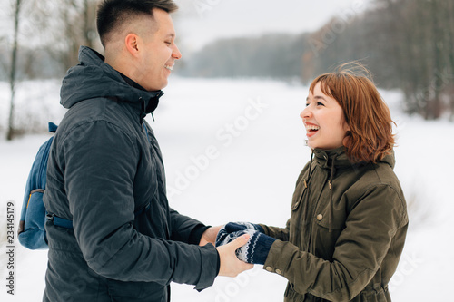 Winter portrait of young beautiful happy smiling couple outdoors. Christmas and winter holidays. Man and woman in snowy park © beatleoff