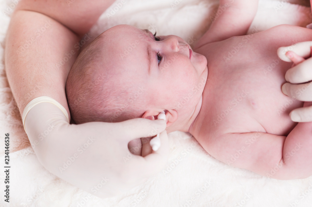 The child at the doctor's office and his ears are cleaned with a cotton swab. The child at the doctor's office and his ears are cleaned with a cotton swab.