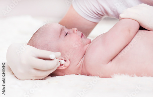The child at the doctor's office and his ears are cleaned with a cotton swab.