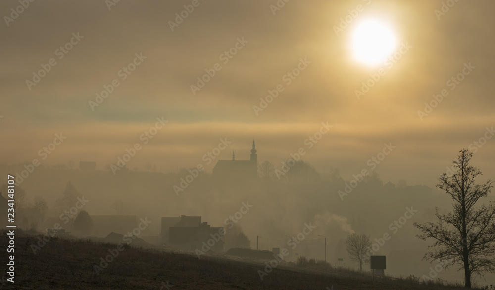 misty sunrise over the church in Jablonce, Poland