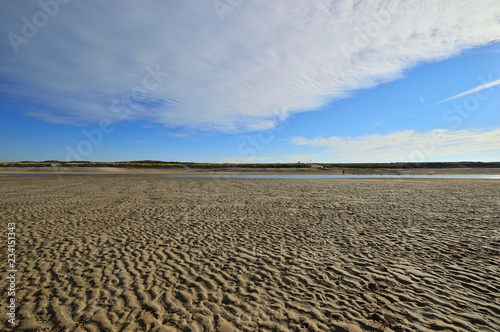 Nadmorskie wybrzeże, plaża i morze pod niebieskim niebem z chmurami.