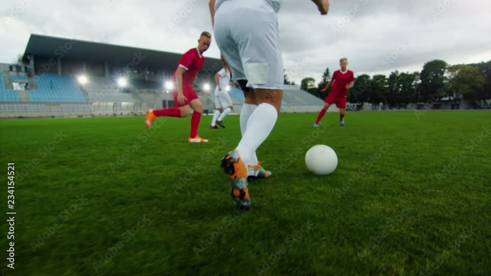  Professional Soccer Player Leads with a Ball, Masterfully Dribbling and Bypassing Sliding Tackles of His Opponents. Two Professional Football Teams Playing. Following Ground Shot.